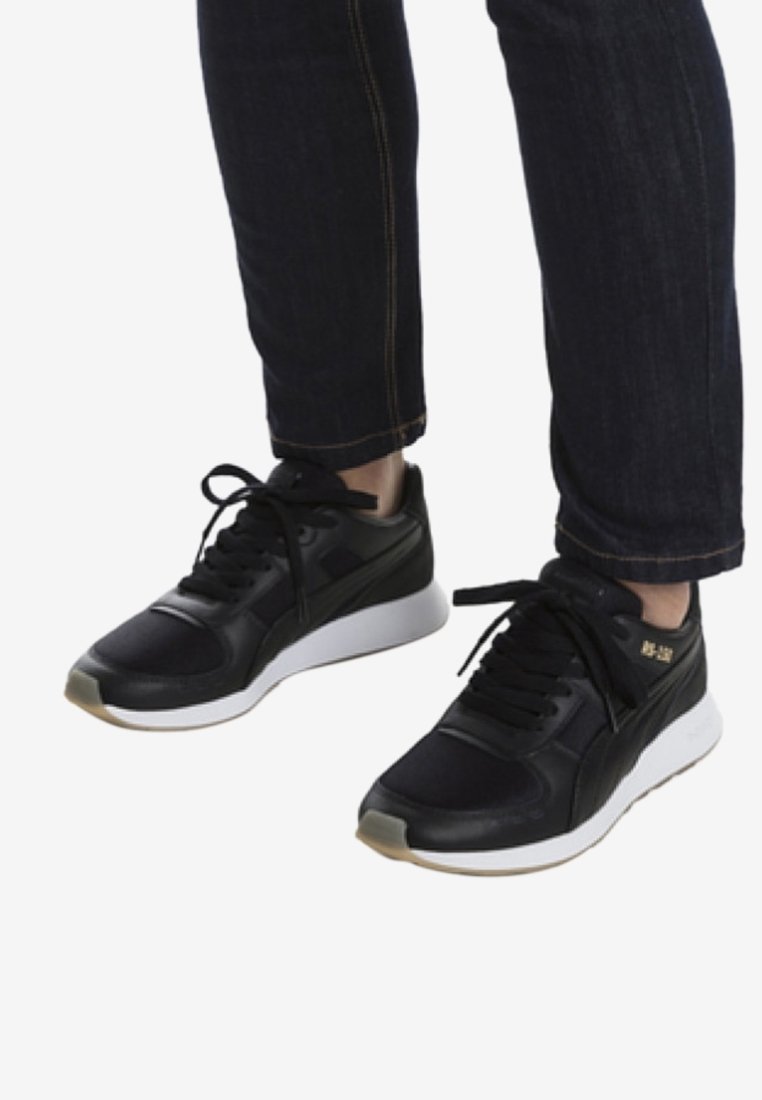 Sneaker sportive nere con una parte superiore tessurizzata, suola intermedia bianca e lacci neri. Presenta un logo dorato discreto sul lato.