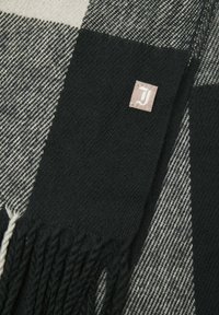 Bufanda a cuadros en blanco y negro con una textura suave, que presenta bordes con flecos y una pequeña etiqueta de marca en la esquina.