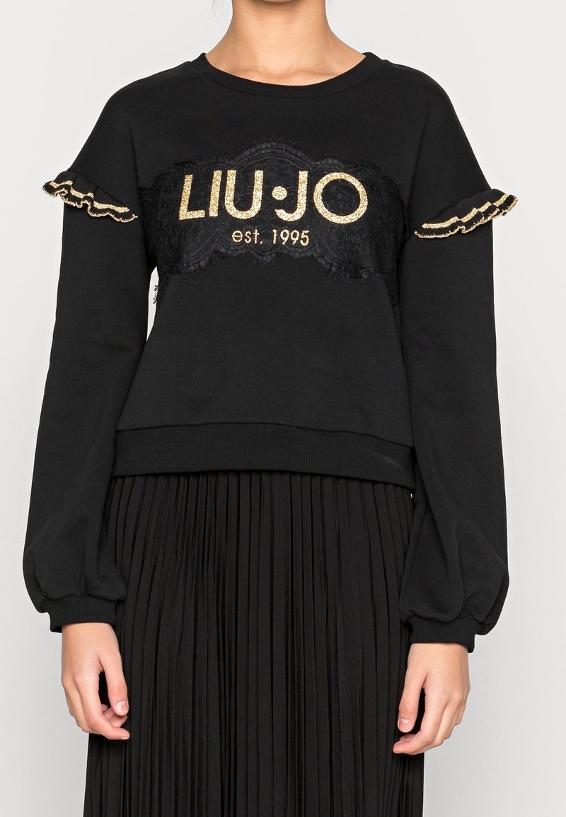 Sudadera negra con mangas largas y abullonadas, que presenta un panel de encaje y el logotipo dorado "LIU-JO est. 1995" en el centro. Acentos de volantes en las mangas.