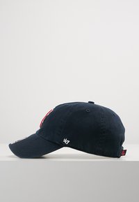 Navy blue cotton cap featuring a curved brim, embroidered logo on the front, and small white detail on the side. Textured finish.