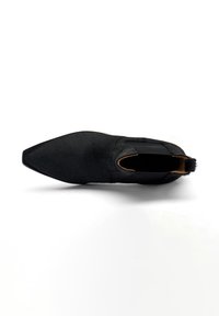 Zapato de cuero negro con textura suave, punta afilada, paneles laterales elásticos y un diseño minimalista sin herrajes ni acentos.