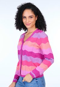 Rosa und lila gestreifte Strickjacke mit V-Ausschnitt, Knopfverschluss und gerippten Bündchen; aus einem weichen Strickmaterial gefertigt.