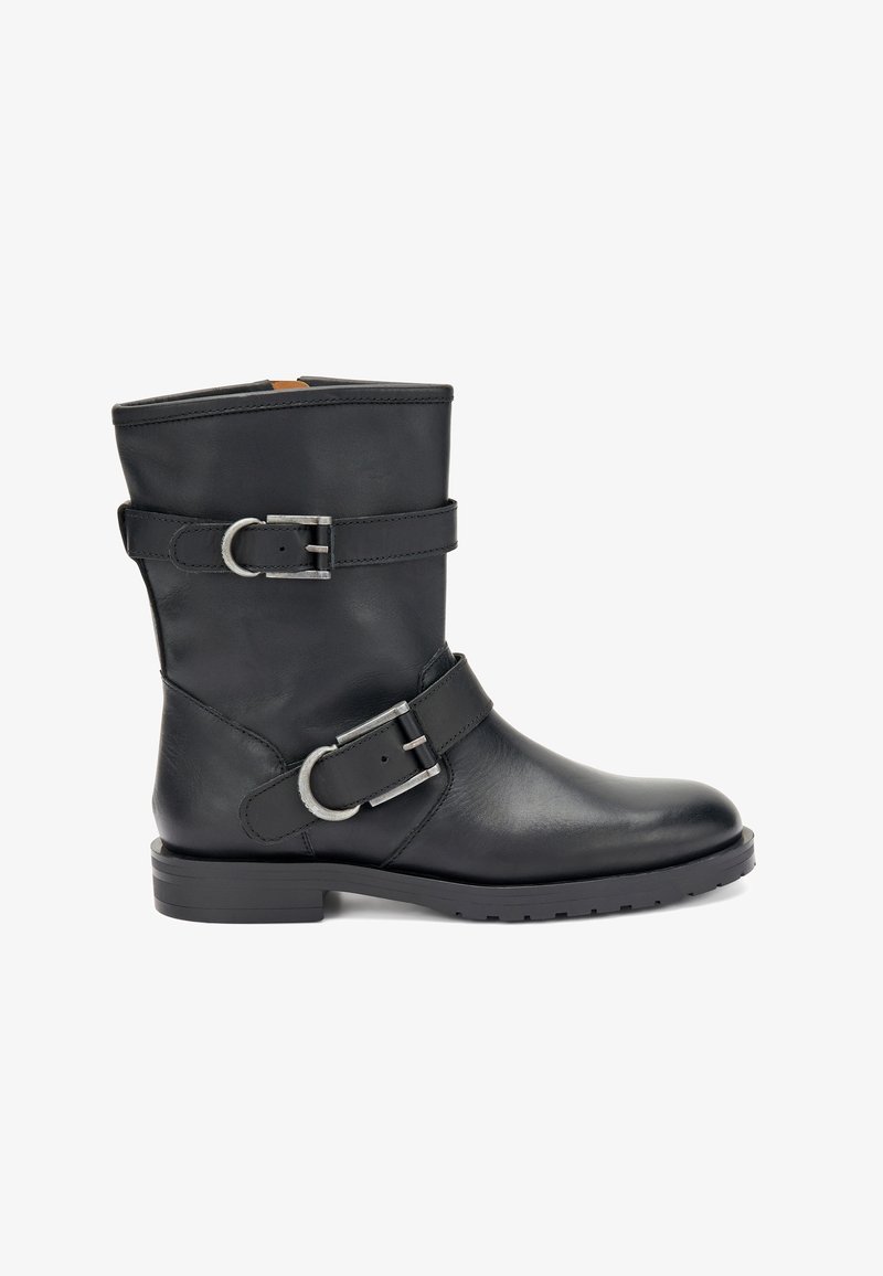 Botín de cuero negro hasta el tobillo con dos correas decorativas y hebillas de plata. Presenta una punta redondeada y una suela de goma texturizada y baja.