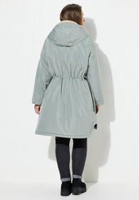Lichtgrijze hoodie met een getailleerde taille en een zachte binnenvoering. Beschikt over lange mouwen en een zoom die tot halverwege de dij komt.