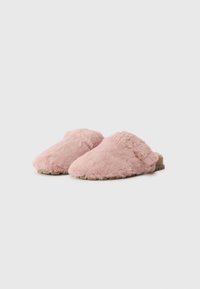 Mules roses en peluche avec une texture douce, un devant arrondi et une semelle plate couleur sable dotée de petits motifs de semelle pour une meilleure adhérence.