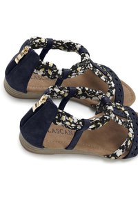 Marineblauwe sandalen met floral-gestikte banden, ritssluiting, geperforeerd ontwerp en een gestructureerde zool. Accenten met gouden hardware.