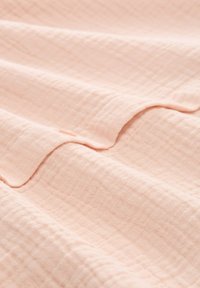 Tessuto rosa chiaro con un motivo strutturato a griglia. Il materiale appare morbido e leggermente stropicciato, presentando bordi sottili e arrotondati.