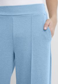 Lichtblauwe broek van textuurstof, met zijzakken en een brede tailleband, met een gladde afwerking en nauwkeurige stikseldetails.