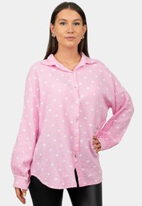 Camicia button-up rosa realizzata in tessuto testurizzato, con un motivo a cuori bianchi, maniche lunghe e collo a camicia.