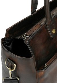 Brązowa skórzana torba o gładkiej fakturze, z zamkiem błyskawicznym, kieszeniami wewnętrznymi oraz metalowymi elementami ozdobnymi.