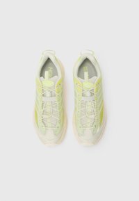 Baskets en maille vert clair avec des accents beige, présentant un bout arrondi, un design à lacets et une semelle texturée pour une meilleure adhérence.