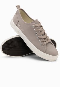 Beige plátěné tenisky s bílou gumovou podrážkou, kulatou špičkou a symetrickým šněrováním. Mají poutko a decentní logo na boku.