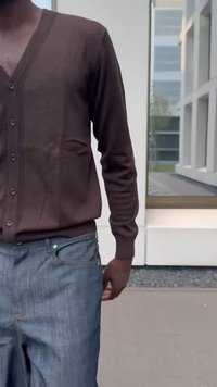 Brun kofta med V-ringning, knäppt fram och långärmad, kombinerad med blå jeans i denim med framfickor och klassisk passform.