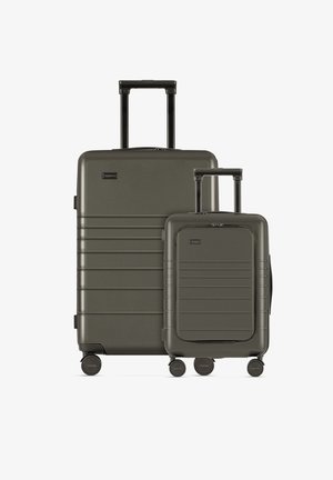 Due trolley abbinati in materiale rigido verde scuro. Il più grande ha un manico telescopico e un design a coste, mentre il più piccolo è compatto con accenti lisci.