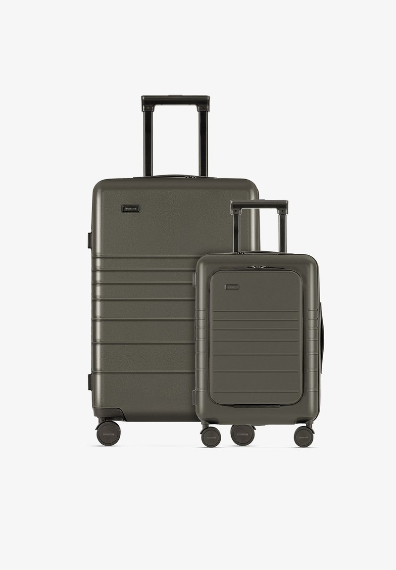 Twee bijpassende koffers van donkergroen hard materiaal. De grotere heeft een telescopische handgreep en een geribbelde uitstraling, terwijl de kleinere compact is met gladde accenten.