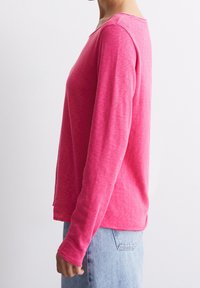 Långärmad rosa topp i ett mjukt, lätt material med en avslappnad passform. Har en rundad halsringning och en något böjd nederkant.