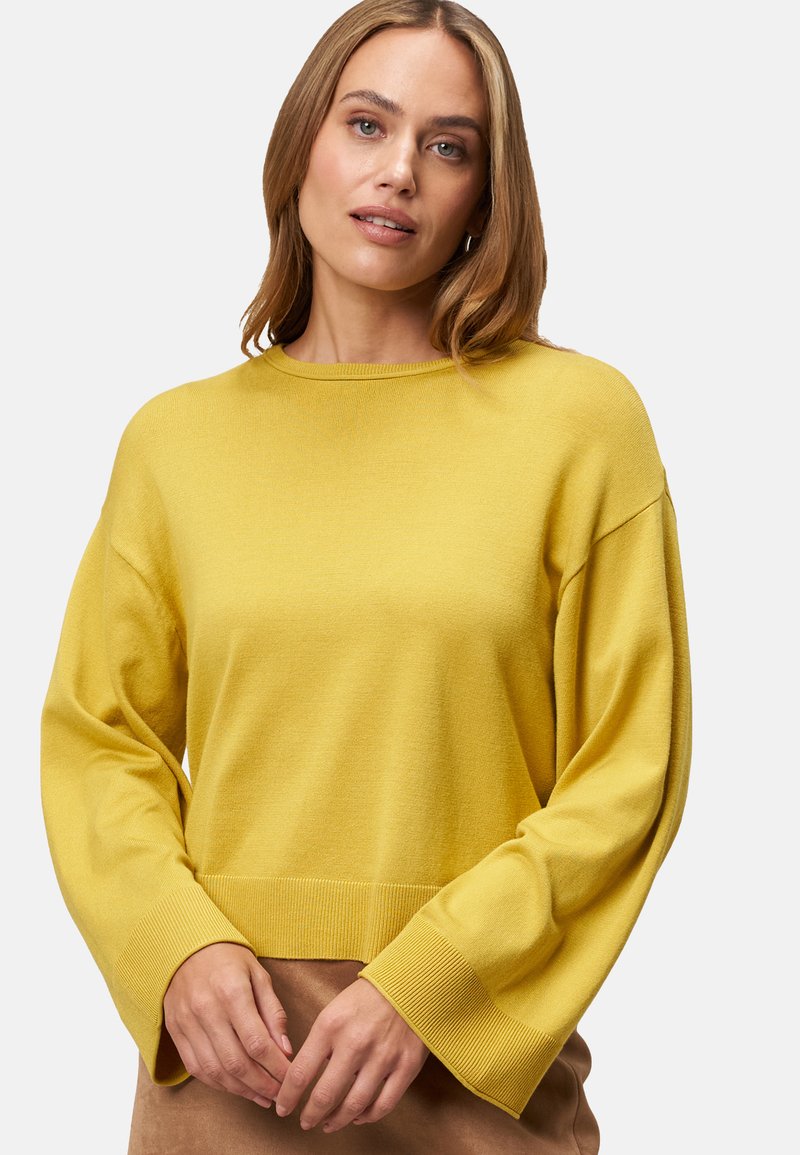Pull en maille jaune avec un col rond, des manches longues et larges, et des poignets côtelés. Texture lisse, design cropped et apparence minimaliste.
