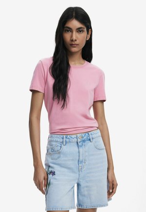 T-shirt rose clair à manches courtes, col rond, avec un petit détail brodé sur la poitrine, assorti à un short en denim bleu clair orné de broderies florales.