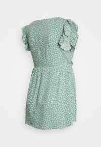 Vestido floral verde com mangas curtas em babados, corpete ajustado e saia drapeada. O tecido apresenta pequenos padrões de flores brancas por toda parte.