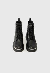 Black leather ankle boots with metallic accents, round toe, reinforced eyelets, and lace-up design. Features pull tab for easy wear.