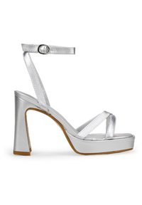 Sandalias plateadas de tacón alto con un acabado metálico brillante, tira en el tobillo y bandas cruzadas en los dedos, presentando un tacón grueso y plataforma.