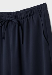 Námořnické modré, lehké kalhoty z tkaniny s elastickým pasem, stažením na šňůrku a bočními kapsami. Hladká textura s plisovanými detaily.