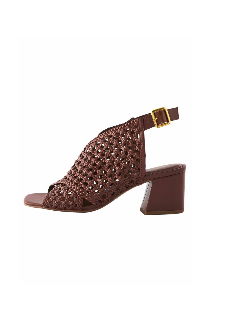 Rudos austos aukštakulniai sandalai su atviru pirštu, reguliuojama kulkšnies juostele ir kvadratiniu bloku kulnu. Yra tekstūruotas raštas.