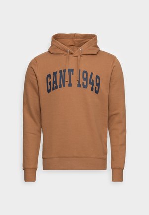 Brązowa bluza z kapturem i długimi rękawami, z granatowym napisem "GANT 1949" na piersi, z kapturem na troczki oraz ściągaczami na mankietach i u dołu.