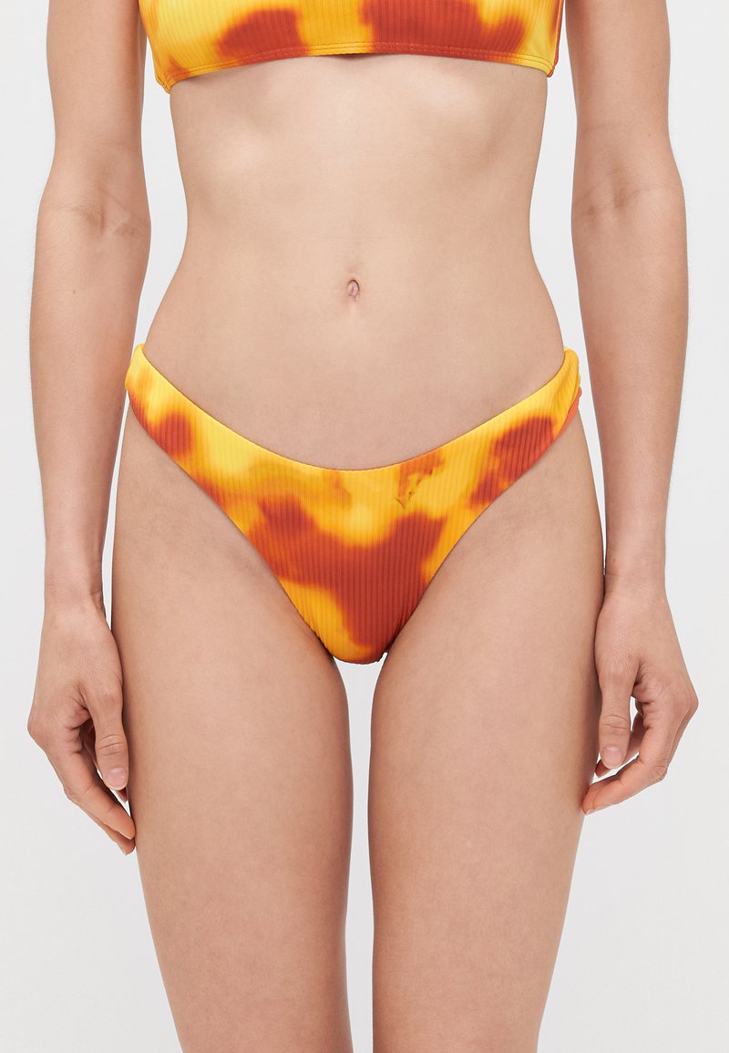 Ženske bikinke z rebrastim vzorcem v rumeni barvi z oranžnimi in rdečimi tie-dye vzorci. Imajo nizko krojenost in gladko teksturo.