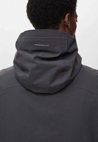 Jachetă impermeabilă gri cu glugă ajustabilă, textură fină și logo subtil pe spate. Design simplu, fără embellishments suplimentare.