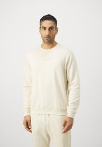 Light beige sweatshirt in soft fabric with a crew neck, ribbed cuffs, and waistband. Features discreet logo in tone-on-tone embroidery.