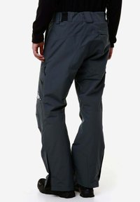 Pantaloni da sci impermeabili grigi con vestibilità rilassata. Le caratteristiche includono tasche laterali e polsini rinforzati. Hardware e cuciture visibili.