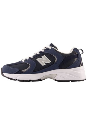Zapatilla deportiva azul marino y negra con suela blanca, cordones blancos y un gran logo "N" en el lateral, mostrada de perfil derecho.