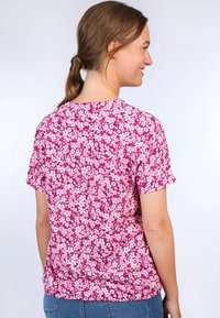 Kurzärmliges Oberteil mit rundem Ausschnitt, das auf leichtem Stoff mit einem pinken Blumenmuster gestaltet ist und für eine entspannte Passform konzipiert wurde.