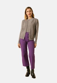 Cardigan gris avec fermeture à boutons, associé à un pantalon violet taille haute. Des bottes noires à talons complètent le look. Design simple et décontracté.