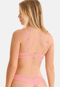 Ensemble de lingerie rose comprenant un soutien-gorge texturé avec des bretelles ajustables et une culotte taille basse assortie, exhibant un motif géométrique sur le tissu.