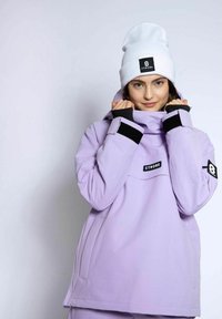 Lilla vandtæt jakke med en struktureret krave, sorte Velcro-ærmer og en frontlomme. Sammen med en hvid hue med et logo-patch.