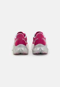 Bakside av treningssko med rosa mesh-overdel, hvite detaljer og en teksturert sølvsåle med geometrisk design.