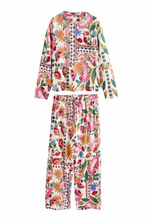 Tweedelige outfit met top met lange mouwen en broek met een meerkleurige grote bloemenprint in roze, oranje, groen, blauw en beige tinten op een witte achtergrond.