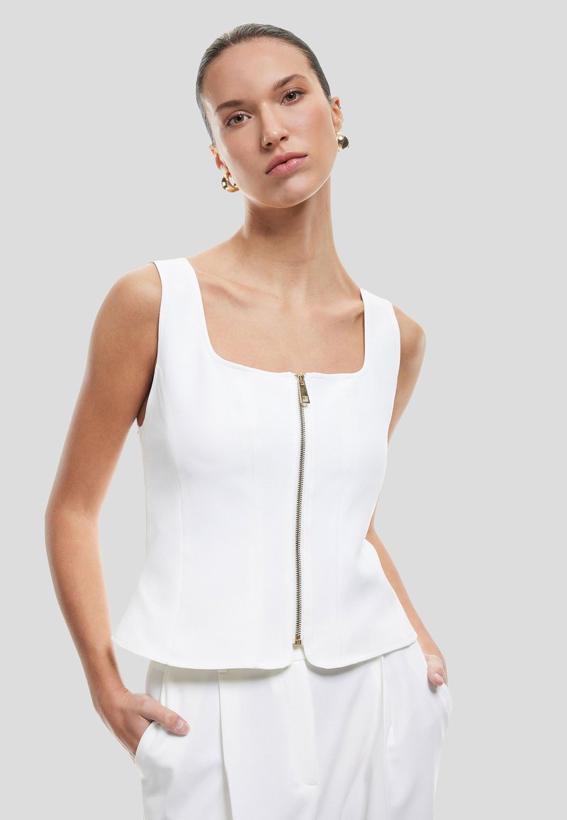Top bianco senza maniche con scollatura quadrata, dotato di chiusura frontale con zip e vestibilità strutturata, texture liscia e design moderno.