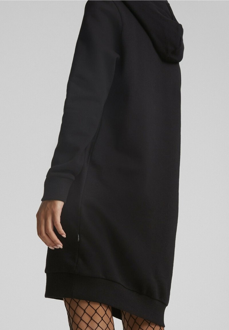 Robe sweat à capuche noire avec manches longues, poignets côtelés, fentes sur les côtés et finition en maille texturée, coupe décontractée et ourlet tombant.