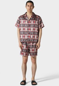Set di camicia a maniche corte con bottoni e pantaloni corti in un brillante motivo rosso e nero, realizzato in tessuto leggero, con una vestibilità ampia e una vita piatta.