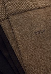 Brown fabric with a textured knit, folded multiple times. Features a darker shade of brown and includes a small logo in a contrasting color.