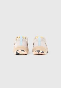 Μπεζ αθλητικά παπούτσια με υφασμάτινο επάνω μέρος με υφή, ανοιχτό μπλε ταμπελα στο τακούνι και πολύχρωμη σόλα με σχέδιο που περιλαμβάνει ροζ και μαύρες λεπτομέρειες.