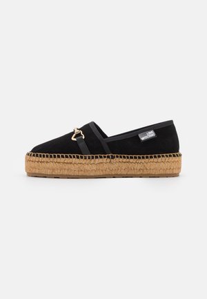 Zwarte suède espadrille met een zool van jute, voorzien van een goudkleurig accent en een elastisch zijpaneel voor gemakkelijk aan- en uittrekken.
