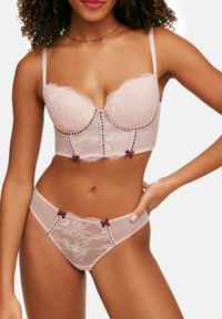 Light pink lingerie set featuring lace detailing, structured cups, adjustable straps, and dark pink accents with bow embellishments.