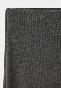 Tissu tricoté côtelé gris foncé plié au bord supérieur, montrant une fine texture verticale et un aspect de matière douce.