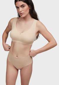 Ensemble de soutien-gorge beige et de culotte taille haute en tissu lisse. Le soutien-gorge est doté de bretelles larges et d'un fermoir avant discret.