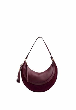 Sac d’épaule rouge foncé en forme de croissant avec un pompon en cuir et une bandoulière réglable sur fond blanc.