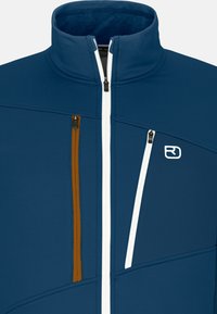 Blauer Reißverschlussjacke mit hohem Kragen. Verfügt über zwei Reißverschlusstaschen; eine in Orange, eine in Weiß. Strukturiertes Gewebe mit geometrischem Design.